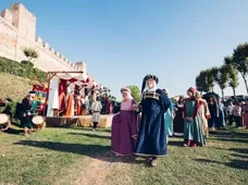 Corteo storico in abiti tradizionali lungo le mura di un borgo