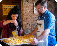 Chef e ospite che preparano insieme un piatto tipico della tradizione locale