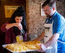 Chef e ospite che preparano insieme un piatto tipico della tradizione locale